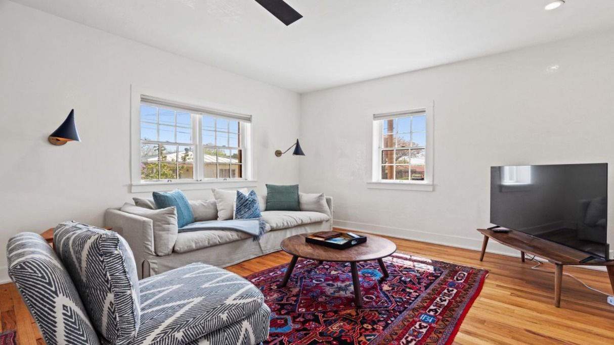 A living room with a sofa, armchair, coffee table, and TV.