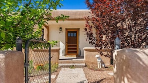 A house with a wooden door, a number '829' on the wall, a small garden with a dog statue, and a metal gate. - 2-bedroom house in lovely Santa Fe (Santa Fe)