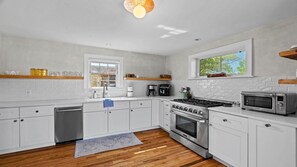 A modern kitchen with white cabinetry, a stainless steel stove, and a microwave. - 2-bedroom house in lovely Santa Fe (Santa Fe)
