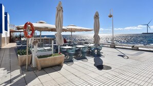 Eine Terrasse mit Sitzgelegenheit im Freien, Rettungsringen und Windkraftanlagen im Hintergrund.