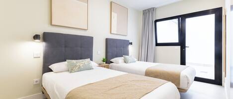 Ein Hotelzimmer mit zwei Betten, einem großen Fenster und einer Schiebetür, die zu einem Außenbereich führt.