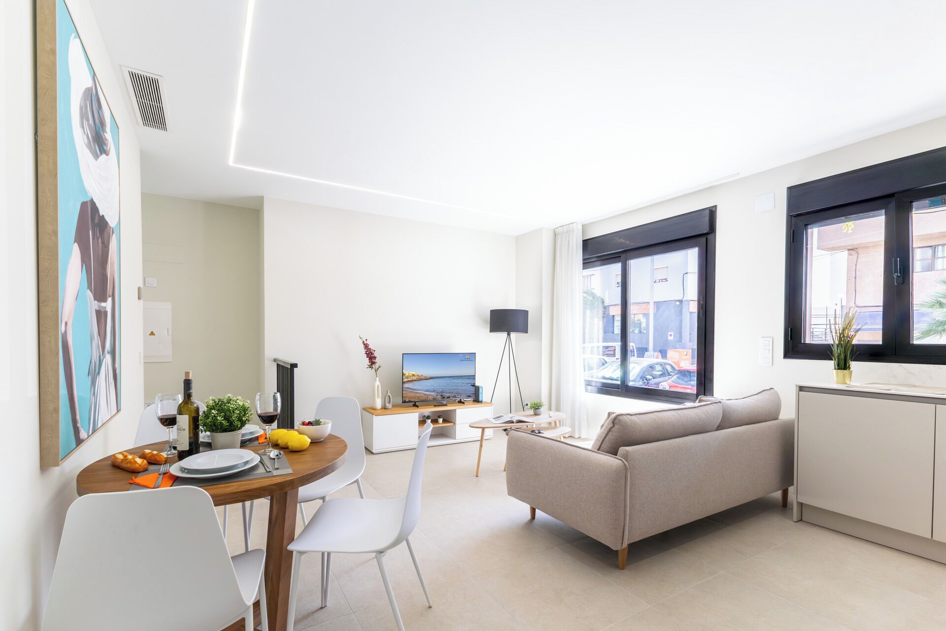 A modern living room with a sofa, dining table, and a TV.