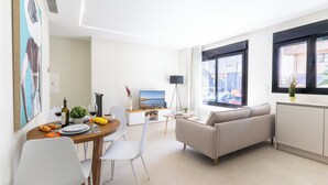 Ein modernes Wohnzimmer mit Sofa, Esstisch und Fernseher.