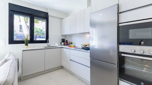 Eine moderne Küche mit weißen Schränken, einem Edelstahlkühlschrank und einem eingebauten Backofen.