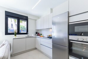 Ett modernt kök med vita skåp, ett kylskåp i rostfritt stål och en inbyggd ugn.
