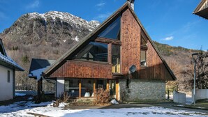 Een modern huis met een schuin dak, grote ramen en een stenen fundering.