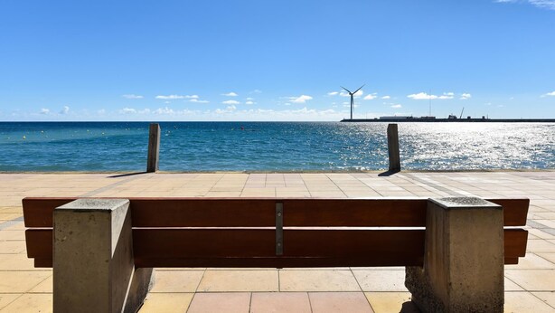 A bench facing a calm sea with a clear sky. - Suites Brisamar V by VillaGranCanaria (Las Palmas de Gran Canaria)