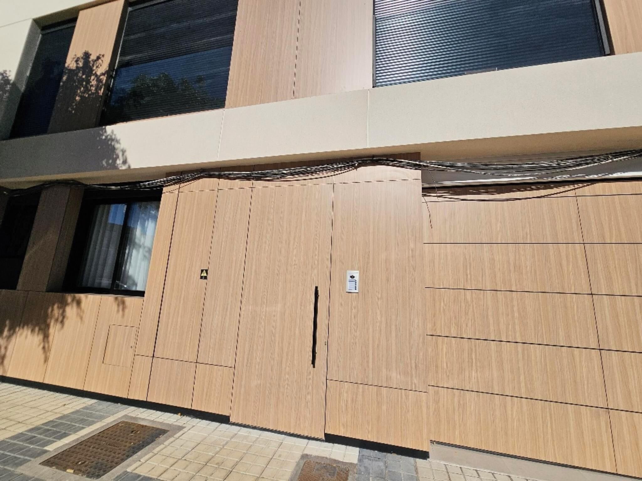Eine zeitgemäße Gebäudefassade mit großen Holzpaneelen, einem Fenster und einer Tür.
