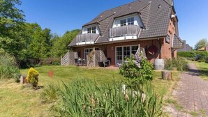 Een herenhuis met twee verdiepingen, een bakstenen gevel, een schuin dak en een voortuin met tuinmeubilair.