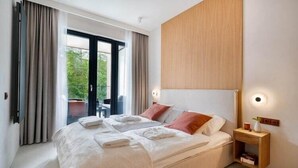 Een moderne hotelkamer met een groot bed, een houten hoofdbord en een nachtkastje met een lamp.