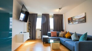 Ein modernes Wohnzimmer mit einer Couch, Couchtisch, Fernseher und Kunstwerken an der Wand.
