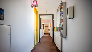 A hallway with a brown carpet, a door on the left, a wall-mounted radiator, and a framed photo collection. - AMA Executive Stay 65m² Near Central Station (Nuremberg)