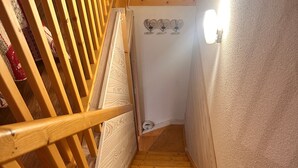 A wooden staircase with a handrail, a textured wall, and a light fixture. - Duplex Apartment for 4 at Les Balcons Du Recoin with Balcony (Chamrousse)