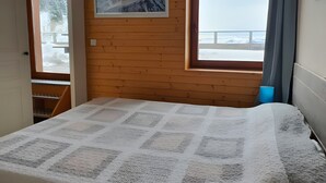 A room with a bed, a window with a view, a framed picture on the wall, and a door leading to a balcony. - Apartment "Les Balcons Du Recoin" for 4 Guests in Chamrousse (Chamrousse)
