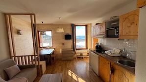 A cozy cabin interior with a wooden dining area, a kitchenette, and a sofa. - Apartment "Les Balcons Du Recoin" for 4 Guests in Chamrousse (Chamrousse)