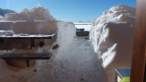 Zona esterna innevata con una panchina in legno e un corrimano in metallo.