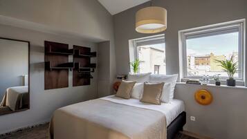 Un dormitorio moderno con una cama grande, una estantería en la pared, un ventanal con vistas y una lámpara colgante.