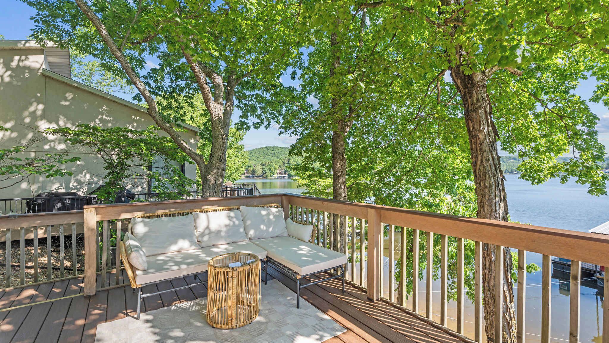 Eine Terrasse mit einer Couch, einem Korbstuhl und einem kleinen Tisch.