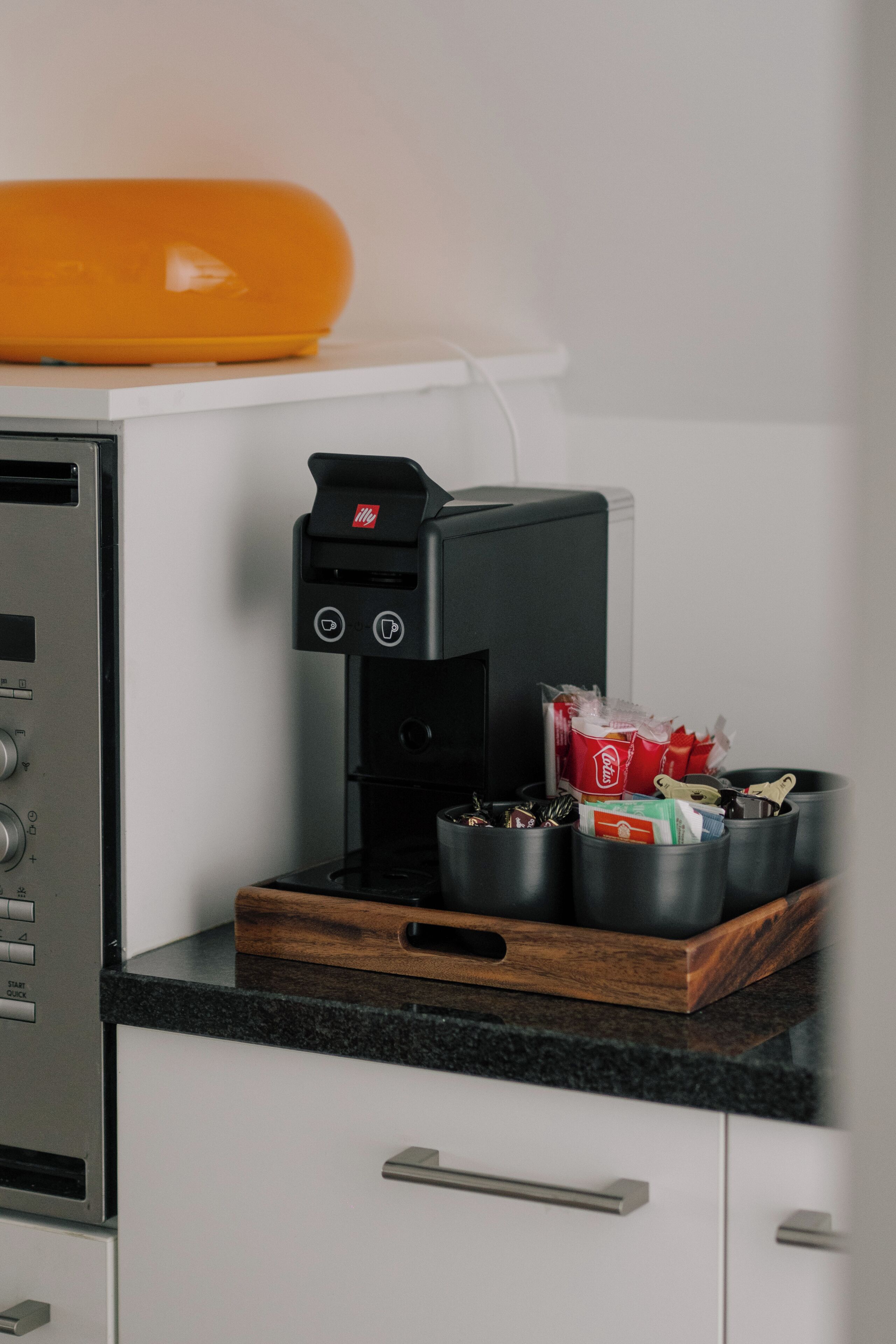 A kitchen with a coffee machine, a toaster, and a tray with food items.