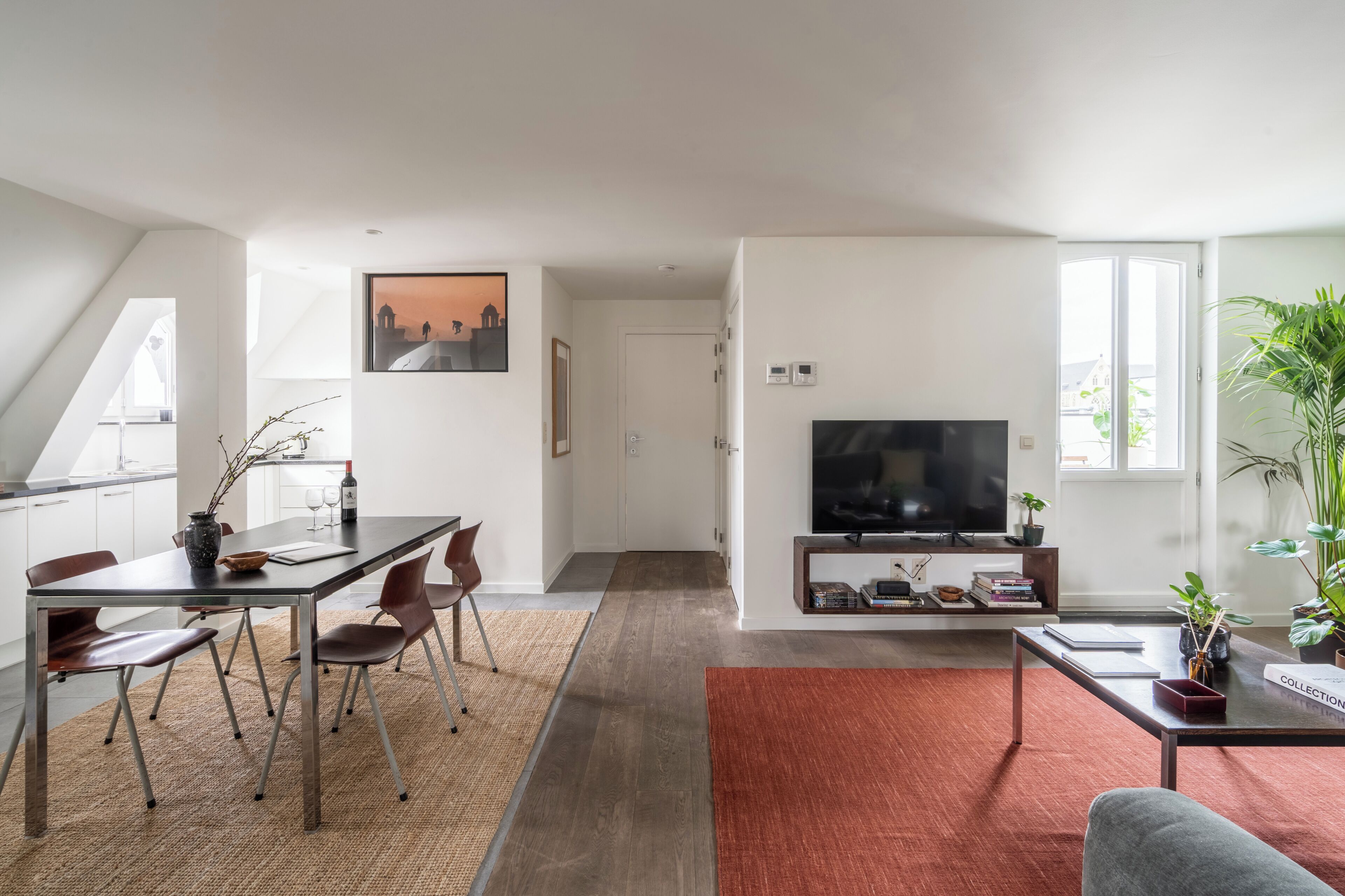 Ein zeitgemäßer Wohnbereich mit Essplatz, Fernseher und großem Fenster.