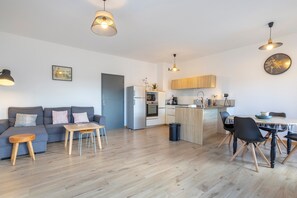 A modern apartment with a living room, dining area, kitchen, and a small island. - L'Urania – Stay in the Heart of Concarneau (Concarneau)