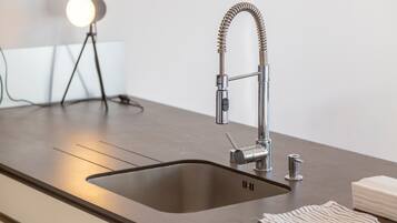 A modern kitchen with a stainless steel sink, a flexible faucet, and a round light on a tripod.