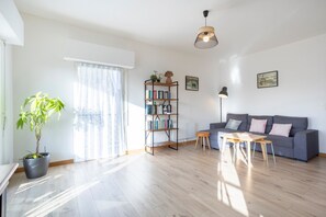 A living room with a grey sofa, a wooden coffee table, a bookshelf, and a potted plant. - L'Urania – Stay in the Heart of Concarneau (Concarneau)