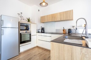 A modern kitchen with a built-in oven, a coffee maker, and a sink. - L'Urania – Stay in the Heart of Concarneau (Concarneau)
