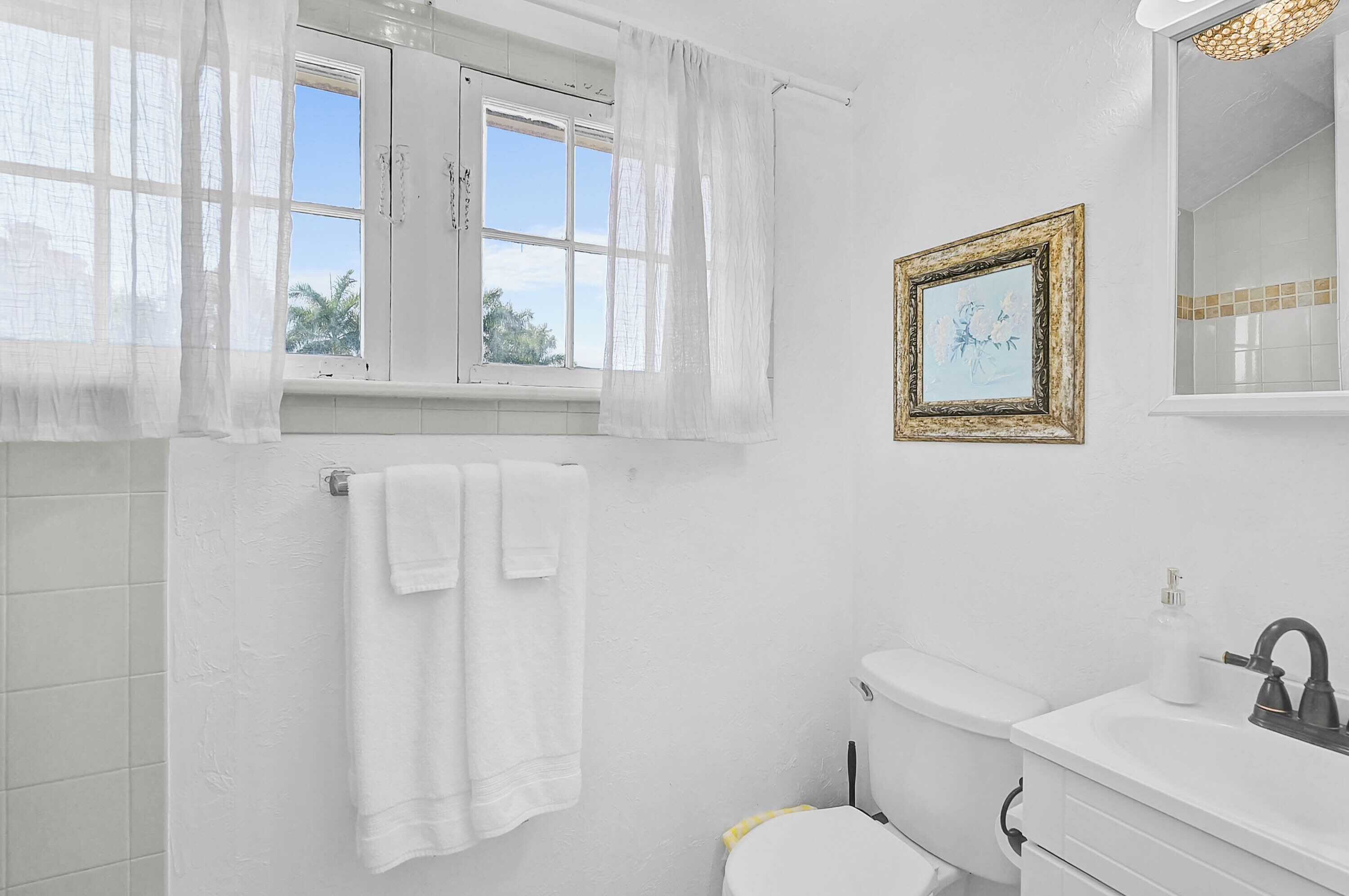 Ein Badezimmer mit Toilette, Waschbecken und einem Fenster mit Vorhängen.