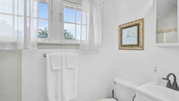 Ein Badezimmer mit Toilette, Waschbecken und einem Fenster mit Vorhängen.
