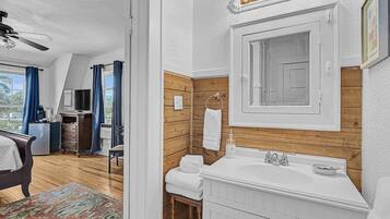 A modern bathroom with a wooden accent wall, a white sink, and a large mirror.