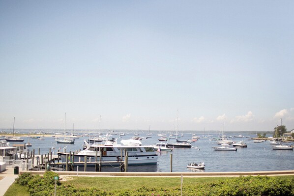 A marina with various boats docked, a grassy area in the foreground, and a clear sky. - The Crown Jewel Apartment in Watch Hill, RI. (Westerly)