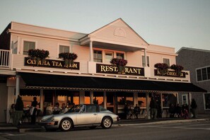 A restaurant with a classic design, featuring a sign that reads "Oly & Lila Tea Room" and "Restroom" on the facade. - The Crown Jewel Apartment in Watch Hill, RI. (Westerly)