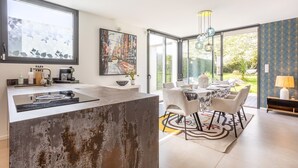 A modern kitchen with a large island, dining area with a table and chairs, and a view of the outdoors. - Exceptional Villa with Garden – 10 Minutes from Combrit Beaches (Combrit)