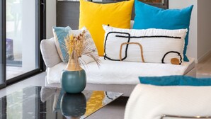 A modern living room with a sofa, a vase with dried plants, and a glass coffee table. - Exceptional Villa with Garden – 10 Minutes from Combrit Beaches (Combrit)