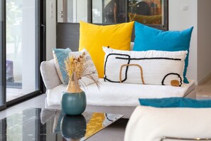 A modern living room with a sofa, a vase with dried plants, and a glass coffee table. - Exceptional Villa with Garden – 10 Minutes from Combrit Beaches (Combrit)