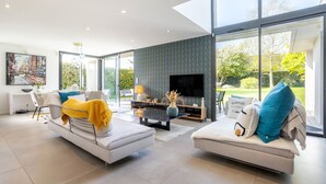 A modern living room with a sofa, a coffee table, a TV, and a large window. - Exceptional Villa with Garden – 10 Minutes from Combrit Beaches (Combrit)