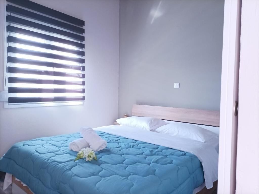 A neatly made bed with a blue quilt, white pillows, and a bouquet of white flowers on the bed.