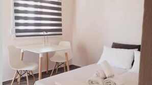 A bedroom with a bed, a desk, two chairs, and a window with blinds. - V&E's Apartments (Ermionida)