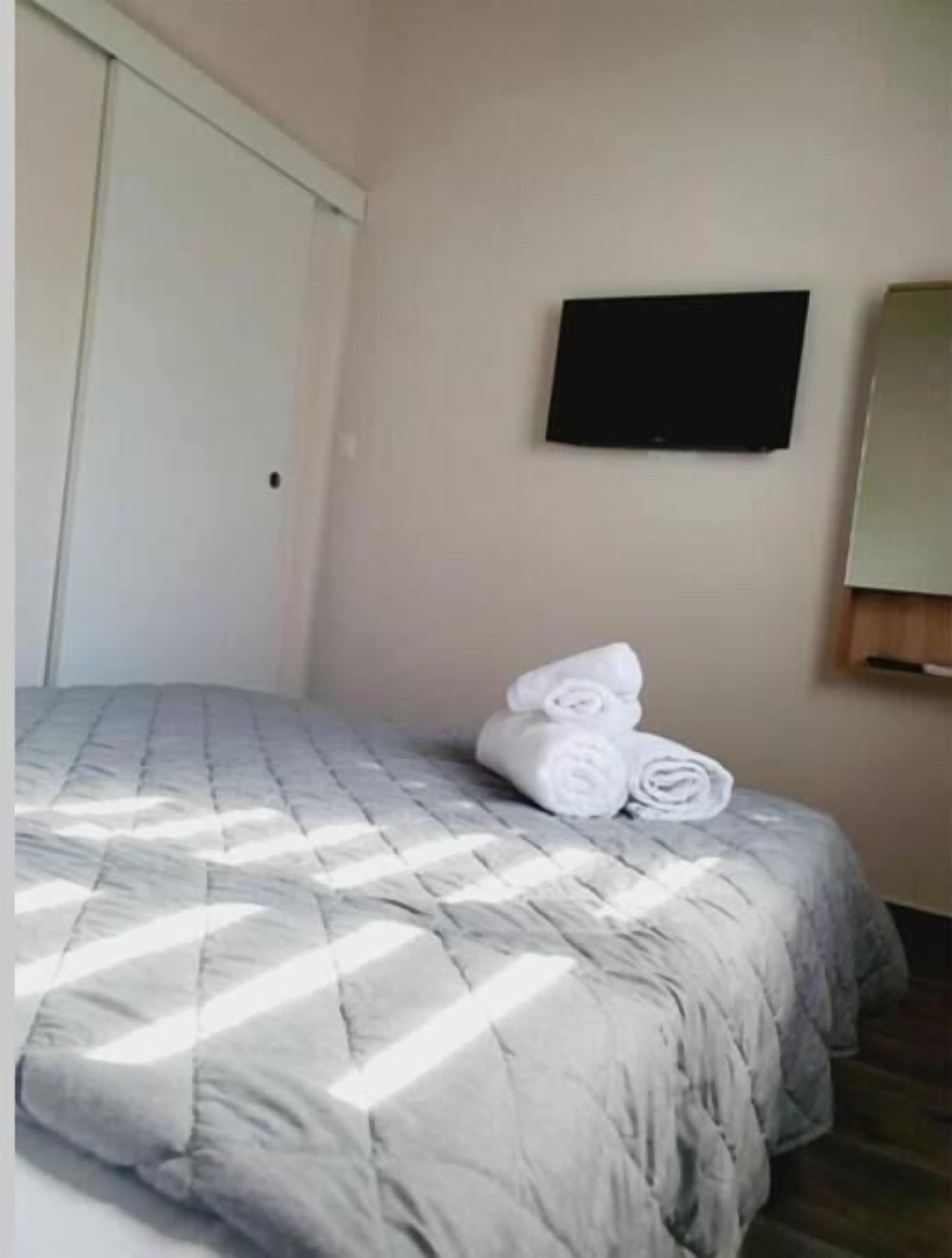 Habitació d'hotel amb un llit, una televisió penjada a la paret i una porta.
