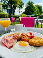 A breakfast plate with eggs, bacon, sausages, beans, and toast.