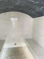 A bathroom with a white marble wall, a black ceiling, and a tiled floor.