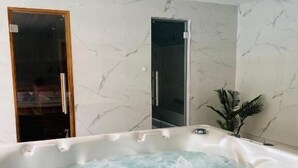 Ein Spa-Raum mit Whirlpool, Marmorwänden und einer Topfpflanze.
