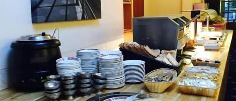 Una mesa de buffet con platos, tazones y una máquina de café.