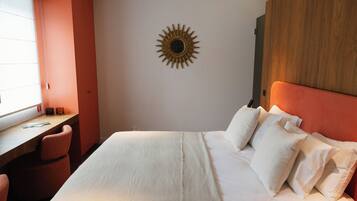 A hotel room with a bed, a desk, and a wall-mounted sun decoration.