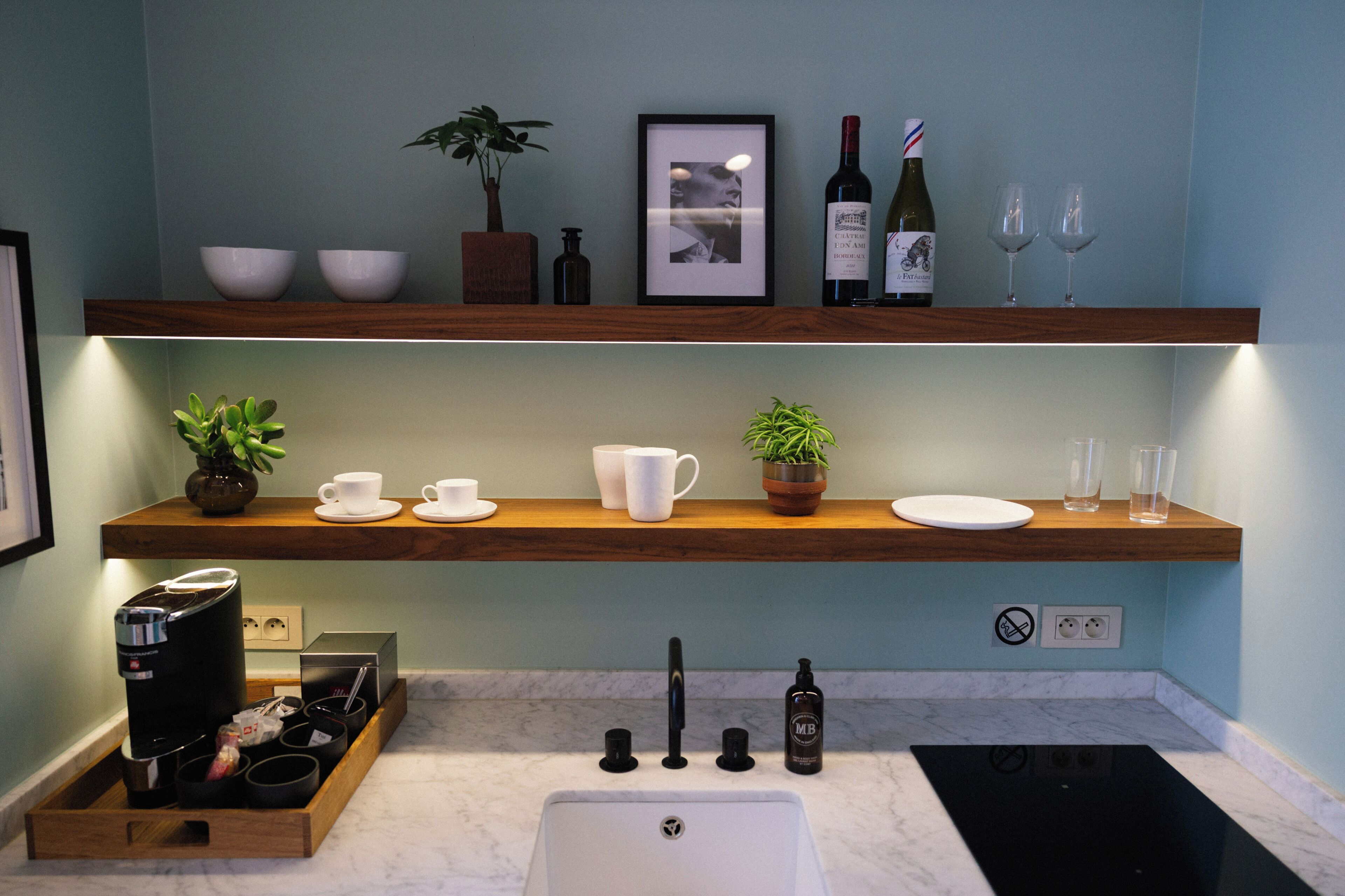 Une cuisine moderne avec des étagères en bois, une machine à café et un évier.