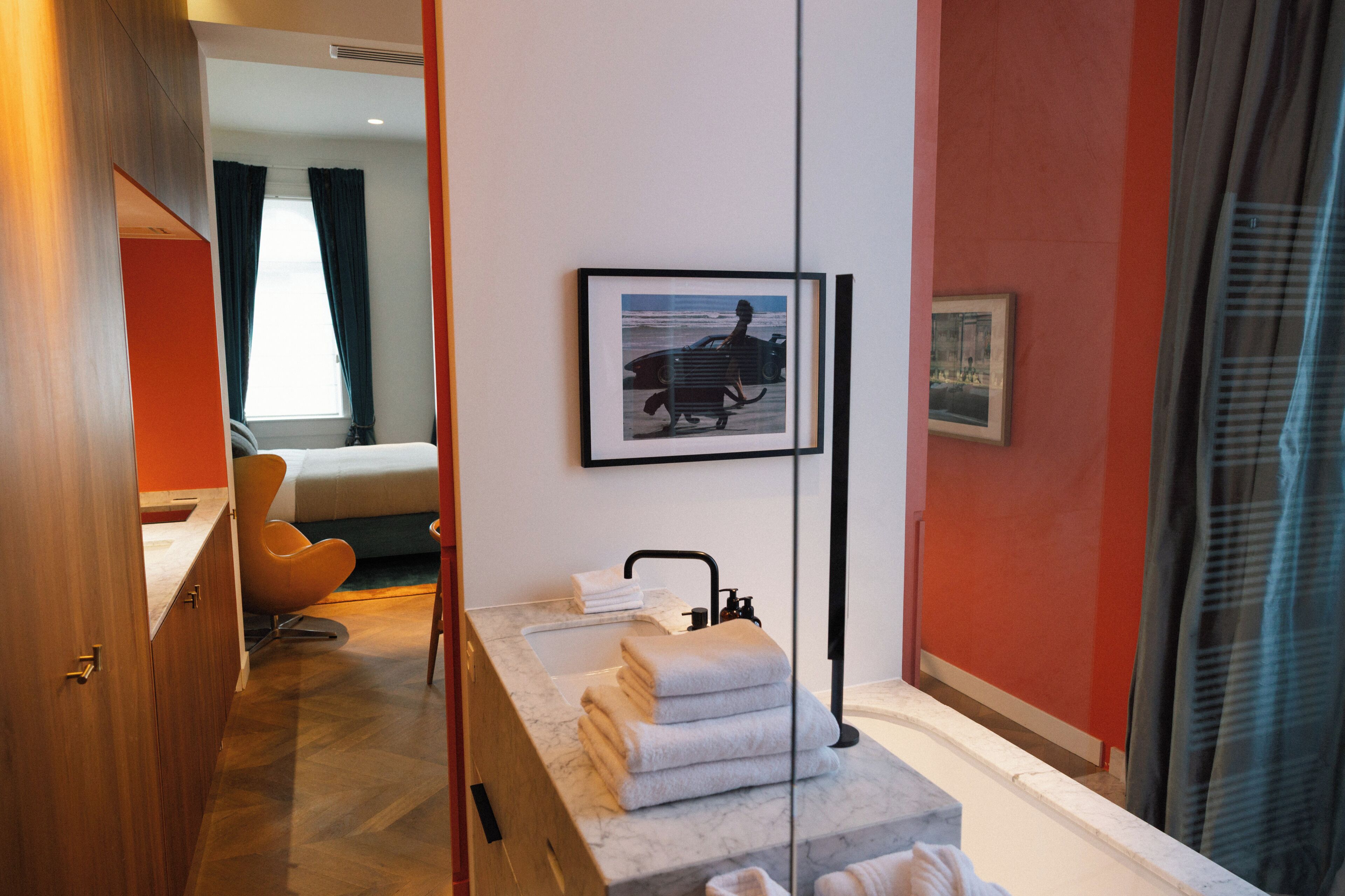 Un bagno moderno con un lavandino in marmo, asciugamani impilati e un quadro incorniciato raffigurante un surfista.