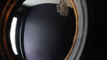 A view through a circular window with a chandelier visible in the reflection.