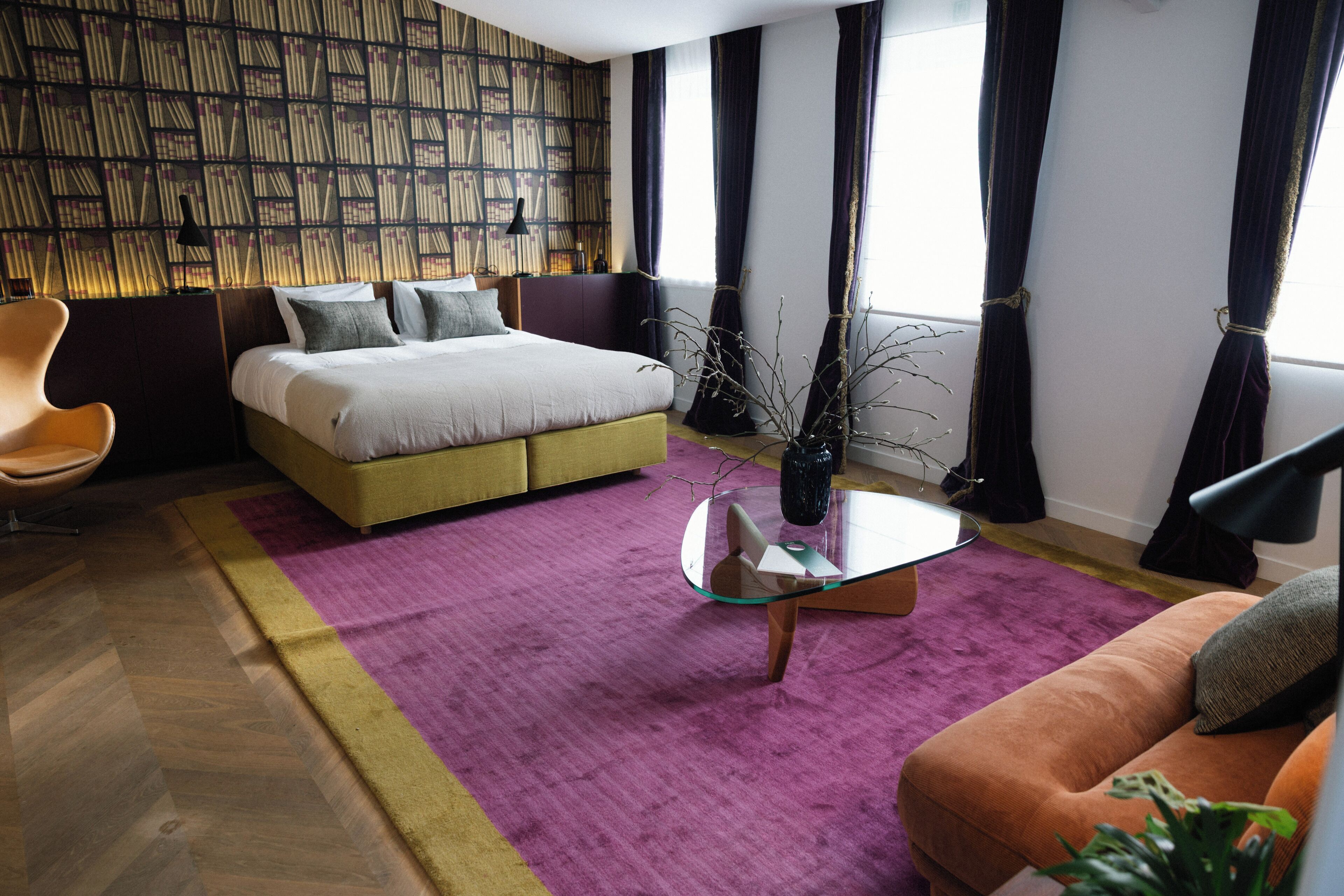 Un dormitorio moderno con una cama grande, una mesa de centro de vidrio, un sofá y una estantería.