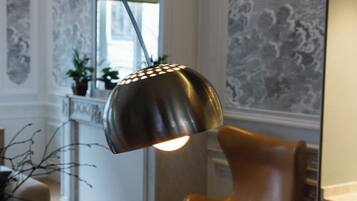 A round table with a vase and an open booklet, a modern chair, and a pendant light fixture.